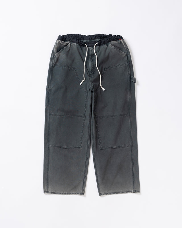 【 商品名：ダブルニーダックペインターパンツ 】

本製品は、レングスをやや長めに設定したブラックカラーのペインターパンツです。ウエスト部分にはナイロンオックス生地で切り替えを施し、ワーク感を抑えた上品なデザインに仕上げています。生地には頒布の中でも最も薄手の11号帆布生地を採用しており、強度・耐久性に優れるとともに、着用を重ねるごとにアタリなどの経年変化を楽しめる素材です。また、水や薬品の使用量を抑えながら生地の凹凸部分のアタリを強調し、同時に自然な脱色感を加える特殊エイジング加工を施しています。