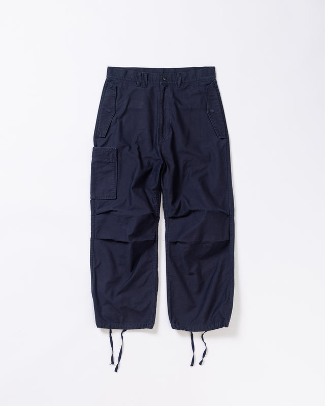 フラップポケットや膝のタック、裾のドローコードなど、ミリタリーディテールを随所に取り入れた1本。通常は内側に配置されるポケットをあえて外側に設けたカーゴポケットが印象的です。ムラ糸で織り上げたバックサテン生地は、独特のハリとコシを持ち、深みのあるネイビーカラーが魅力です。