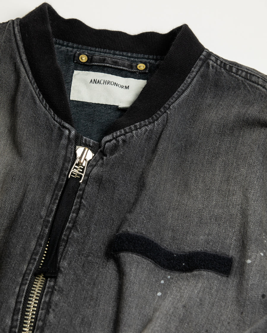 【 商品名：エイジングデュアルデニムMA-1 】

本製品は、ブランドのメイン素材であるデニムを使用し、ディティールを忠実に再現しながらシルエットを整えたブラックカラーのMA-1ジャケットです。中綿は入っていませんが、ライトオンスデニムを採用し、二重縫製によって柔らかく程よい肉感のある着心地に仕上げています。生地にはムラ糸を使用した8ozデニムを採用しており、シャープなムラ形状と粗野な風合いがより一層ヴィンテージ感を引き立てます。さらに加工には、全体にリアルなアタリ感を与えるエイジング加工を施し、深みのある表情を持たせています。