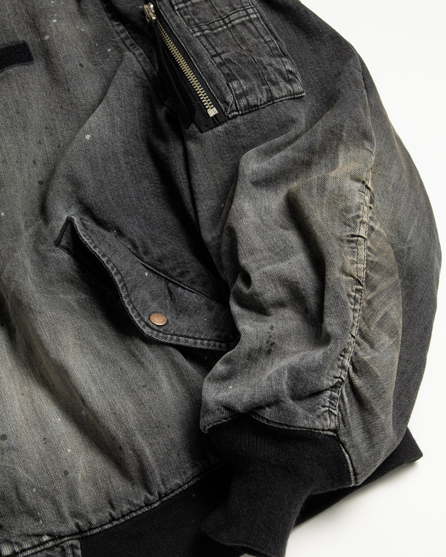 【 商品名：エイジングデュアルデニムMA-1 】

本製品は、ブランドのメイン素材であるデニムを使用し、ディティールを忠実に再現しながらシルエットを整えたブラックカラーのMA-1ジャケットです。中綿は入っていませんが、ライトオンスデニムを採用し、二重縫製によって柔らかく程よい肉感のある着心地に仕上げています。生地にはムラ糸を使用した8ozデニムを採用しており、シャープなムラ形状と粗野な風合いがより一層ヴィンテージ感を引き立てます。さらに加工には、全体にリアルなアタリ感を与えるエイジング加工を施し、深みのある表情を持たせています。