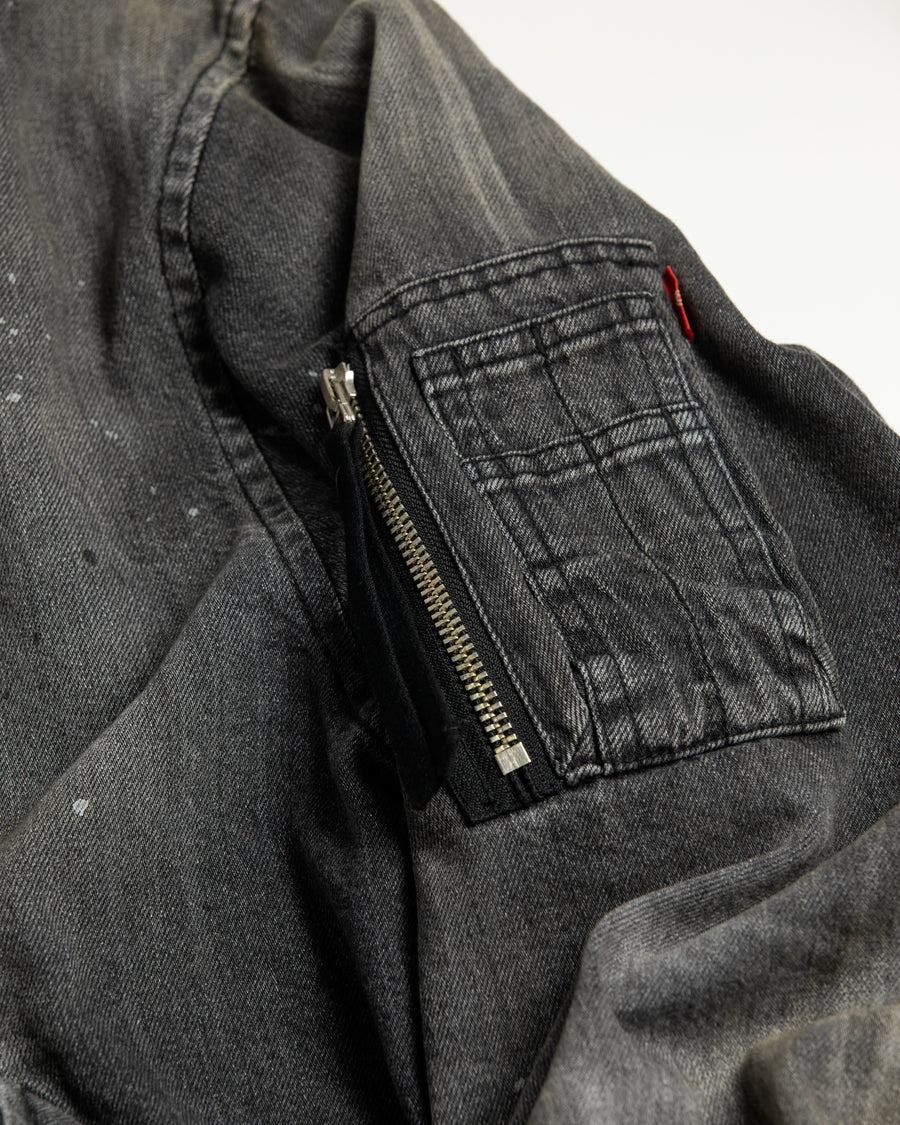 【 商品名：エイジングデュアルデニムMA-1 】

本製品は、ブランドのメイン素材であるデニムを使用し、ディティールを忠実に再現しながらシルエットを整えたブラックカラーのMA-1ジャケットです。中綿は入っていませんが、ライトオンスデニムを採用し、二重縫製によって柔らかく程よい肉感のある着心地に仕上げています。生地にはムラ糸を使用した8ozデニムを採用しており、シャープなムラ形状と粗野な風合いがより一層ヴィンテージ感を引き立てます。さらに加工には、全体にリアルなアタリ感を与えるエイジング加工を施し、深みのある表情を持たせています。