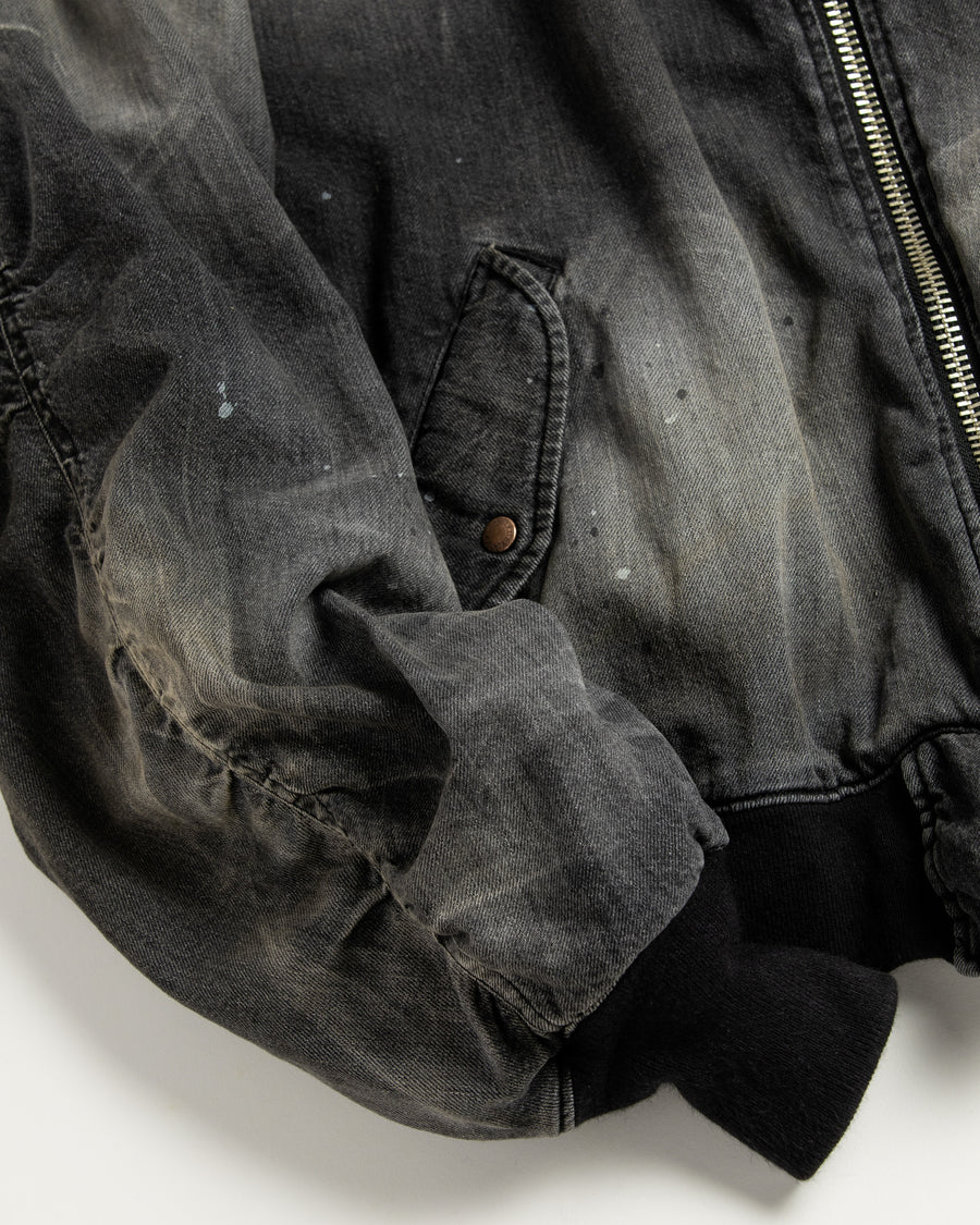 【 商品名：エイジングデュアルデニムMA-1 】

本製品は、ブランドのメイン素材であるデニムを使用し、ディティールを忠実に再現しながらシルエットを整えたブラックカラーのMA-1ジャケットです。中綿は入っていませんが、ライトオンスデニムを採用し、二重縫製によって柔らかく程よい肉感のある着心地に仕上げています。生地にはムラ糸を使用した8ozデニムを採用しており、シャープなムラ形状と粗野な風合いがより一層ヴィンテージ感を引き立てます。さらに加工には、全体にリアルなアタリ感を与えるエイジング加工を施し、深みのある表情を持たせています。