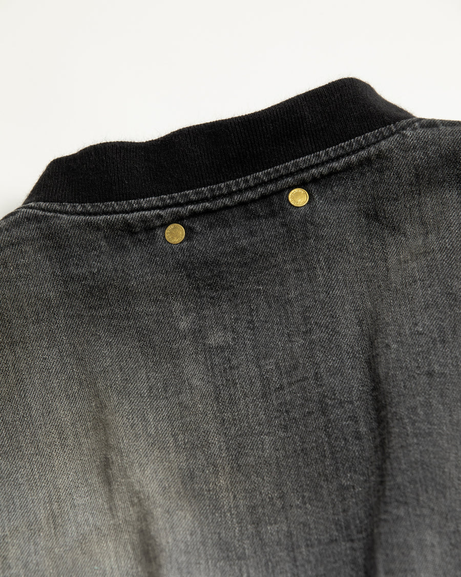 【 商品名：エイジングデュアルデニムMA-1 】

本製品は、ブランドのメイン素材であるデニムを使用し、ディティールを忠実に再現しながらシルエットを整えたブラックカラーのMA-1ジャケットです。中綿は入っていませんが、ライトオンスデニムを採用し、二重縫製によって柔らかく程よい肉感のある着心地に仕上げています。生地にはムラ糸を使用した8ozデニムを採用しており、シャープなムラ形状と粗野な風合いがより一層ヴィンテージ感を引き立てます。さらに加工には、全体にリアルなアタリ感を与えるエイジング加工を施し、深みのある表情を持たせています。