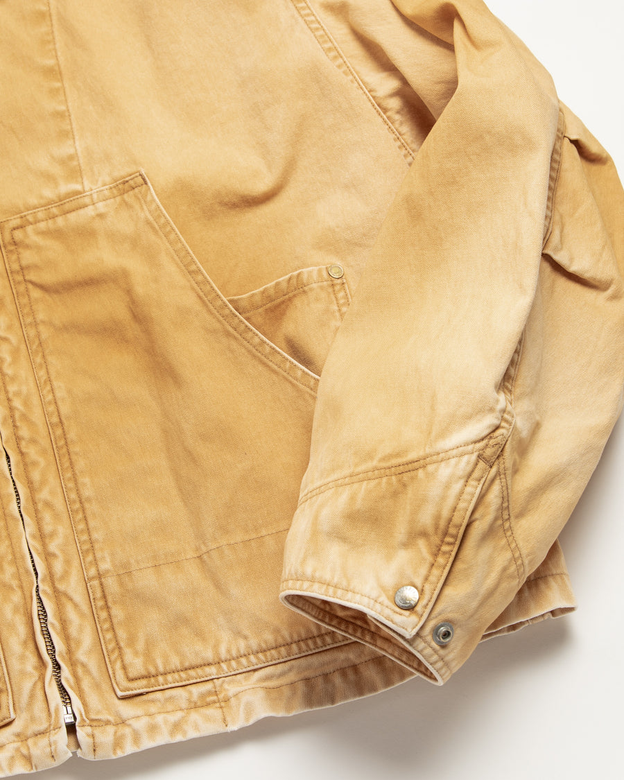シルエットはゆとりのある身幅とややクロップド丈で設計しており、イエローカラーの鮮やかなトーンがレイヤードスタイルをより引き立てます。インナーアイテムとの重ね着がしやすいバランスに仕上げています。
生地には頒布の中で最も薄手の11号帆布を採用しており、強度・耐久性に優れるだけでなく、着用を重ねるごとにアタリなどの経年変化を楽しめる素材です。また、特殊エイジング加工を施すことで、水や薬品の使用量を抑えながら生地の凹凸が強調され、イエローの色味に自然なフェード感を加えています。