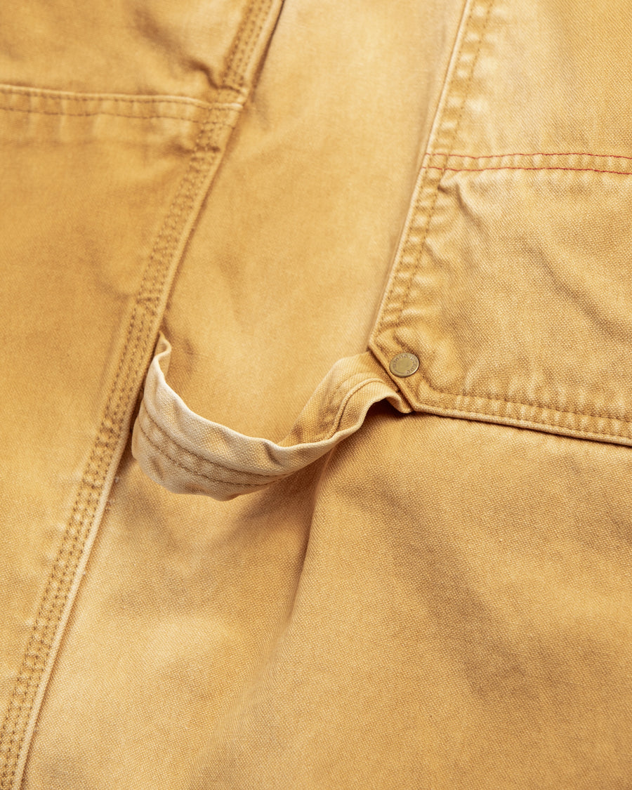 【 商品名：ダブルニーダックペインターパンツ 】

本製品は、レングスをやや長めに設定したイエローカラーのペインターパンツです。ウエスト部分にはナイロンオックス生地で切り替えを施し、ワーク感を抑えたデザインに仕上げています。生地には頒布の中でも最も薄手の11号帆布生地を使用しており、強度・耐久性に優れるだけでなく、着用を重ねるごとにアタリなどの経年変化を楽しめる素材です。また、水や薬品の使用量を抑えつつ生地の凹凸部分のアタリを強調し、同時に自然な脱色感を生み出す特殊エイジング加工を施しています。