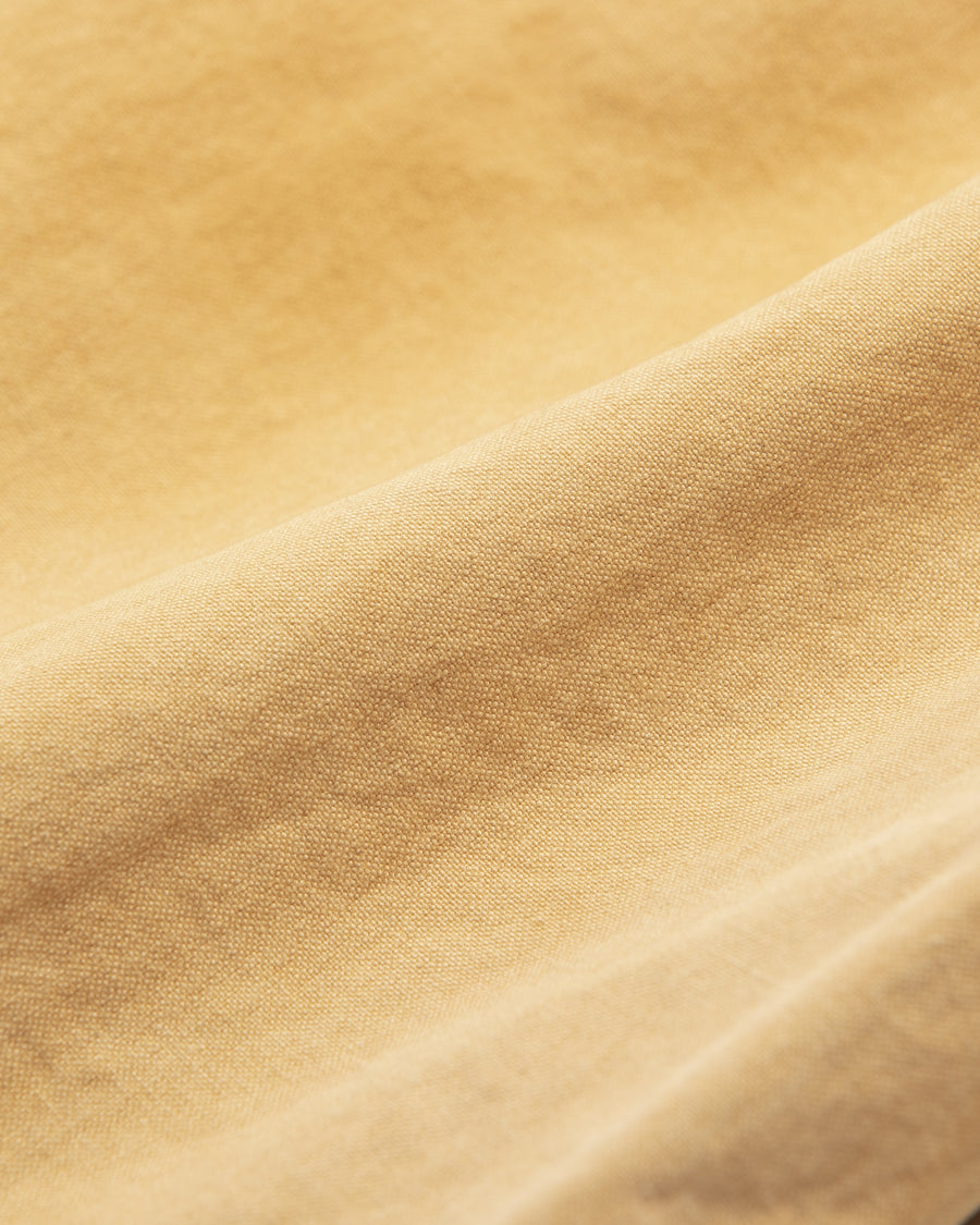 【 商品名：ダブルニーダックペインターパンツ 】

本製品は、レングスをやや長めに設定したイエローカラーのペインターパンツです。ウエスト部分にはナイロンオックス生地で切り替えを施し、ワーク感を抑えたデザインに仕上げています。生地には頒布の中でも最も薄手の11号帆布生地を使用しており、強度・耐久性に優れるだけでなく、着用を重ねるごとにアタリなどの経年変化を楽しめる素材です。また、水や薬品の使用量を抑えつつ生地の凹凸部分のアタリを強調し、同時に自然な脱色感を生み出す特殊エイジング加工を施しています。