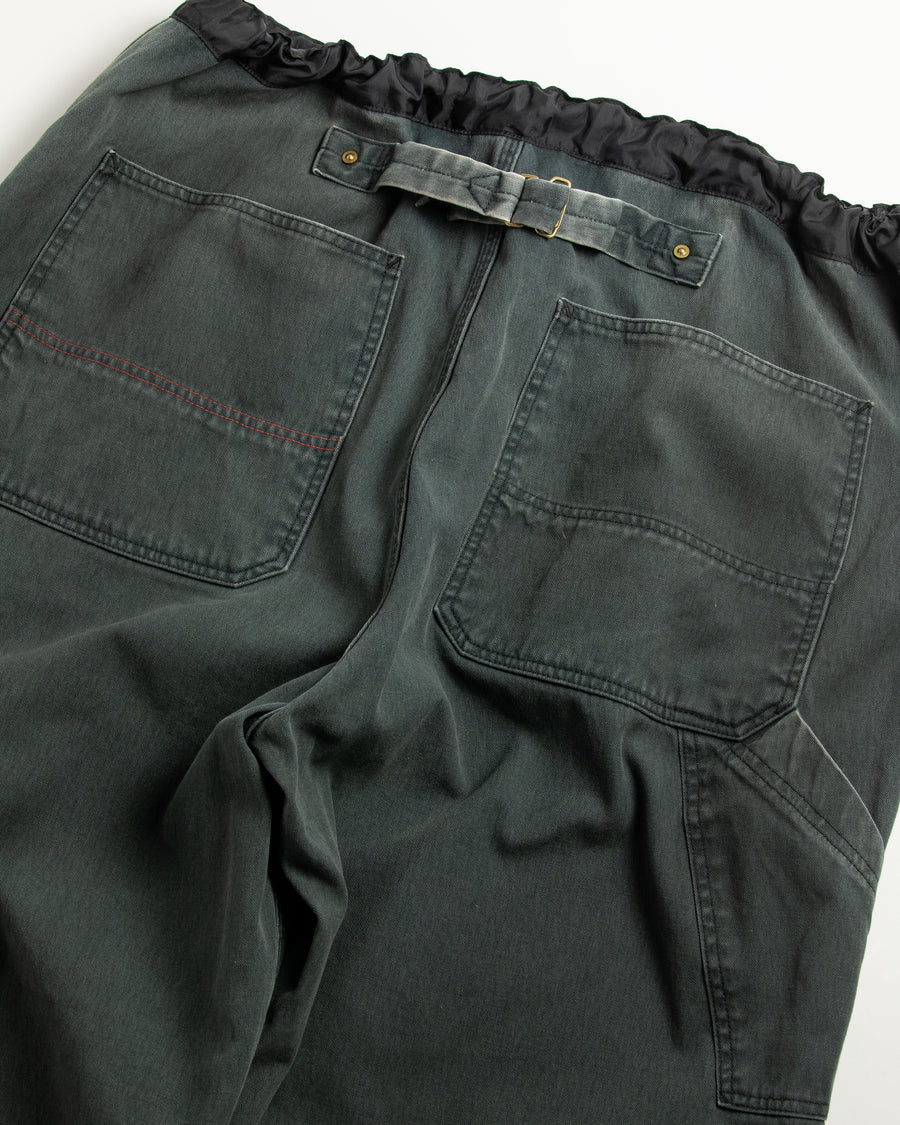 【 商品名：ダブルニーダックペインターパンツ 】

本製品は、レングスをやや長めに設定したブラックカラーのペインターパンツです。ウエスト部分にはナイロンオックス生地で切り替えを施し、ワーク感を抑えた上品なデザインに仕上げています。生地には頒布の中でも最も薄手の11号帆布生地を採用しており、強度・耐久性に優れるとともに、着用を重ねるごとにアタリなどの経年変化を楽しめる素材です。また、水や薬品の使用量を抑えながら生地の凹凸部分のアタリを強調し、同時に自然な脱色感を加える特殊エイジング加工を施しています。