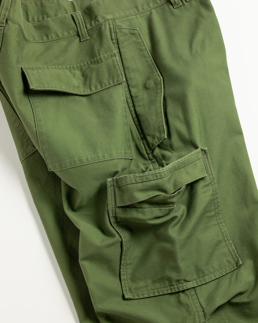 フラップポケットや膝のタック、裾のドローコードなど、ミリタリーディテールを随所に取り入れた1本。通常は内側に配置されるポケットをあえて外側に設けたカーゴポケットが印象的です。ムラ糸で織り上げたバックサテン生地は、独特のハリとコシを持ち、深みのあるオリーブカラーが魅力です。