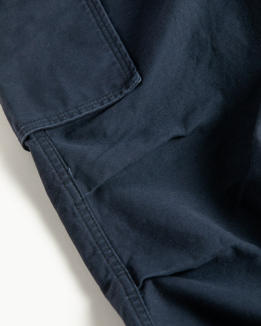 フラップポケットや膝のタック、裾のドローコードなど、ミリタリーディテールを随所に取り入れた1本。通常は内側に配置されるポケットをあえて外側に設けたカーゴポケットが印象的です。ムラ糸で織り上げたバックサテン生地は、独特のハリとコシを持ち、深みのあるネイビーカラーが魅力です。