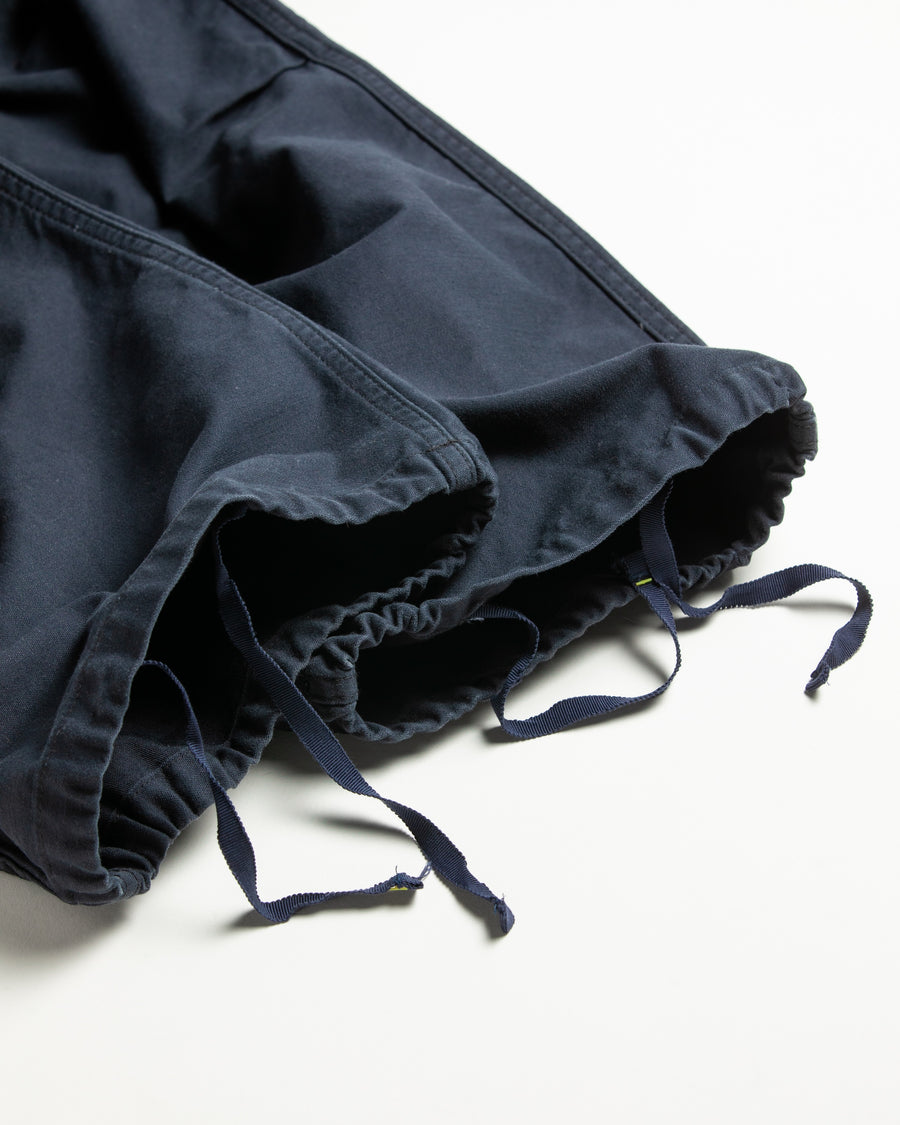 フラップポケットや膝のタック、裾のドローコードなど、ミリタリーディテールを随所に取り入れた1本。通常は内側に配置されるポケットをあえて外側に設けたカーゴポケットが印象的です。ムラ糸で織り上げたバックサテン生地は、独特のハリとコシを持ち、深みのあるネイビーカラーが魅力です。