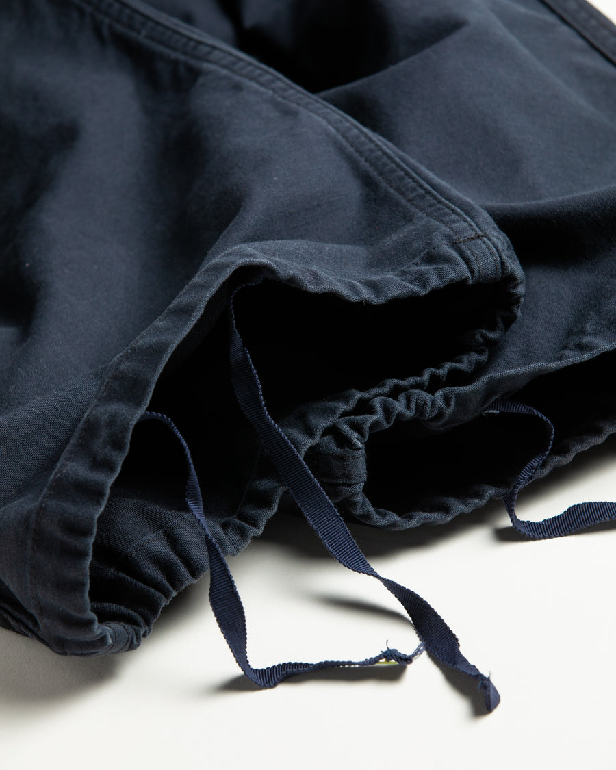 フラップポケットや膝のタック、裾のドローコードなど、ミリタリーディテールを随所に取り入れた1本。通常は内側に配置されるポケットをあえて外側に設けたカーゴポケットが印象的です。ムラ糸で織り上げたバックサテン生地は、独特のハリとコシを持ち、深みのあるネイビーカラーが魅力です。