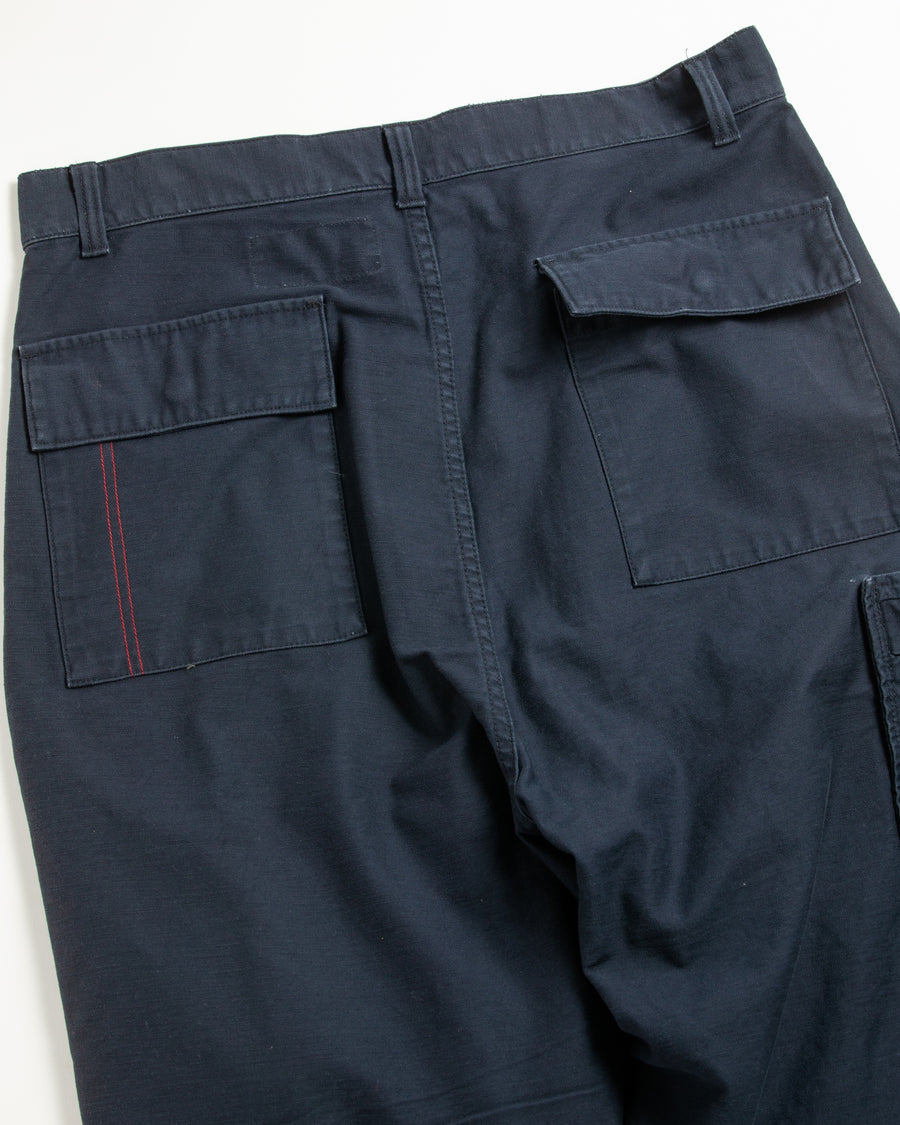 フラップポケットや膝のタック、裾のドローコードなど、ミリタリーディテールを随所に取り入れた1本。通常は内側に配置されるポケットをあえて外側に設けたカーゴポケットが印象的です。ムラ糸で織り上げたバックサテン生地は、独特のハリとコシを持ち、深みのあるネイビーカラーが魅力です。