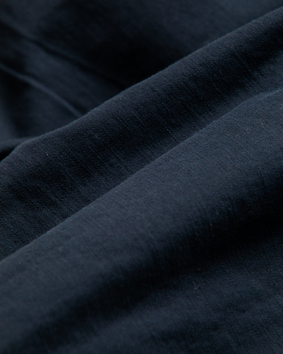 フラップポケットや膝のタック、裾のドローコードなど、ミリタリーディテールを随所に取り入れた1本。通常は内側に配置されるポケットをあえて外側に設けたカーゴポケットが印象的です。ムラ糸で織り上げたバックサテン生地は、独特のハリとコシを持ち、深みのあるネイビーカラーが魅力です。