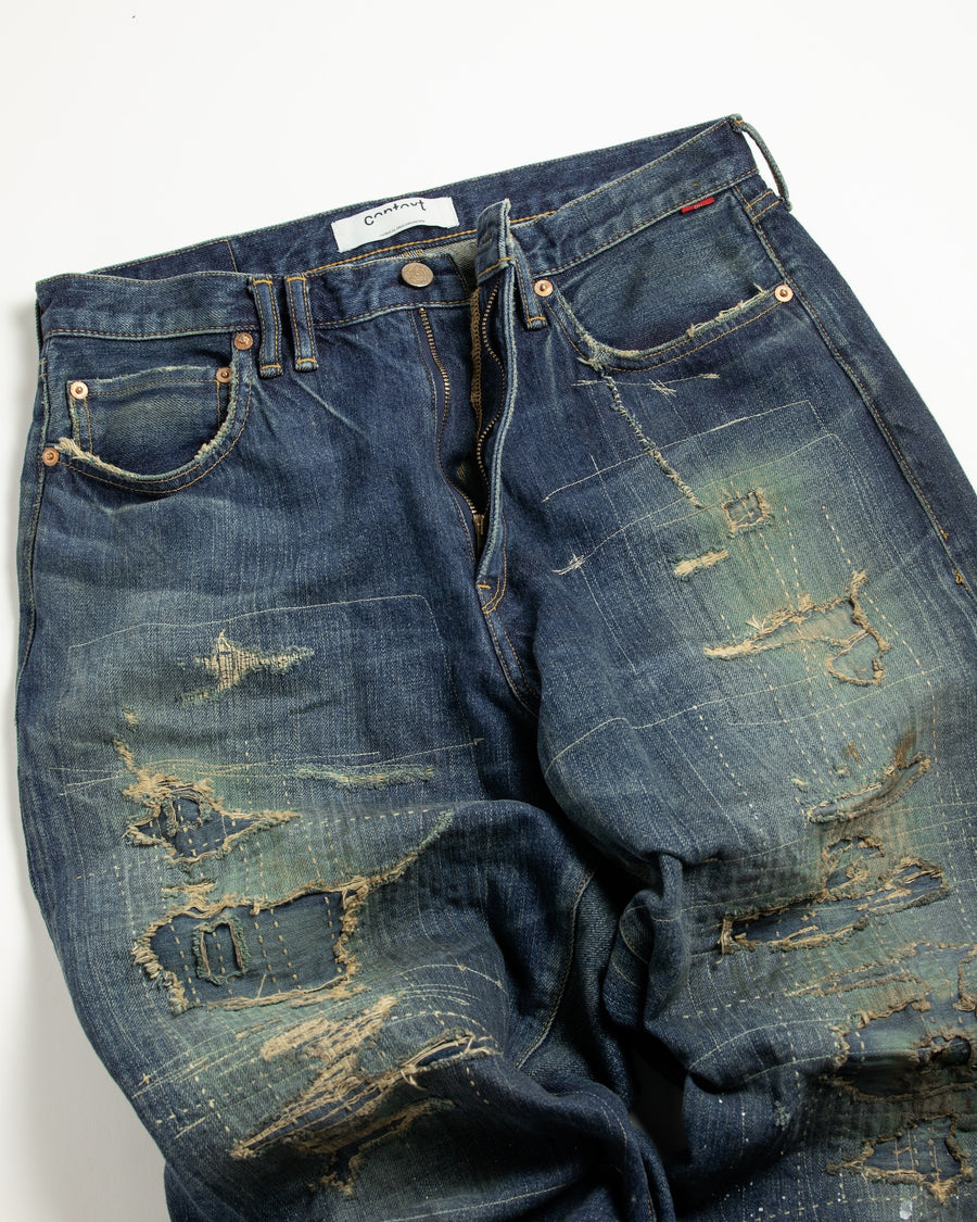12.5ozデニムを使用したテーパードシルエット。
濃色エイジングとブリーチを組み合わせたハードダメージ加工。
複数の当て布でパッチワークリメイクを施した存在感ある一本です。
A tapered silhouette crafted from 12.5oz denim.
Features heavy damage with dark aging and bleach treatments.
Finished with patchwork-style remake details using multiple fabric patches.