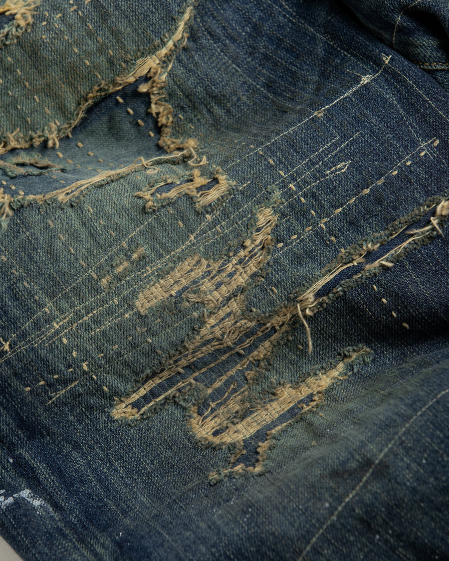 12.5ozデニムを使用したテーパードシルエット。
濃色エイジングとブリーチを組み合わせたハードダメージ加工。
複数の当て布でパッチワークリメイクを施した存在感ある一本です。
A tapered silhouette crafted from 12.5oz denim.
Features heavy damage with dark aging and bleach treatments.
Finished with patchwork-style remake details using multiple fabric patches.