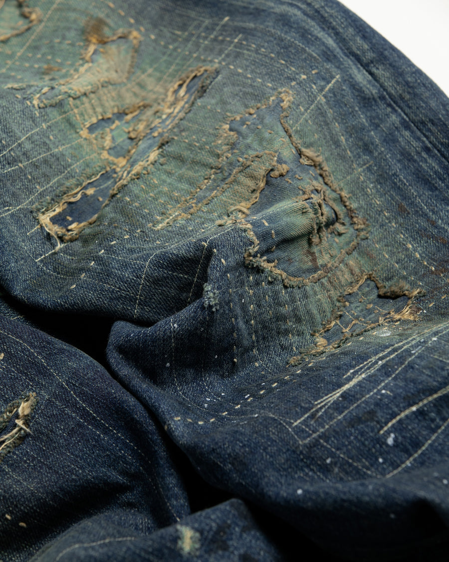 12.5ozデニムを使用したテーパードシルエット。
濃色エイジングとブリーチを組み合わせたハードダメージ加工。
複数の当て布でパッチワークリメイクを施した存在感ある一本です。
A tapered silhouette crafted from 12.5oz denim.
Features heavy damage with dark aging and bleach treatments.
Finished with patchwork-style remake details using multiple fabric patches.