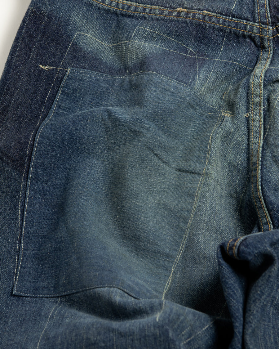 12.5ozデニムを使用したテーパードシルエット。
濃色エイジングとブリーチを組み合わせたハードダメージ加工。
複数の当て布でパッチワークリメイクを施した存在感ある一本です。
A tapered silhouette crafted from 12.5oz denim.
Features heavy damage with dark aging and bleach treatments.
Finished with patchwork-style remake details using multiple fabric patches.