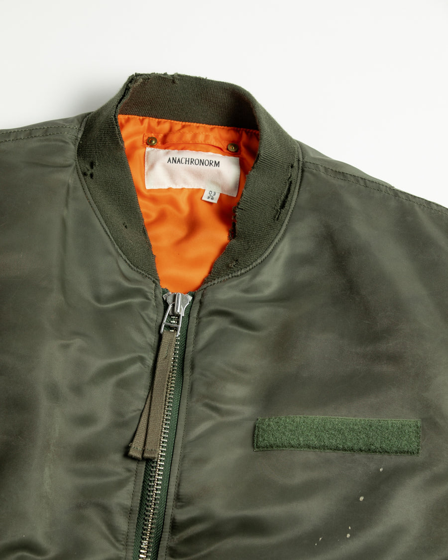 忠実なディテールを保ちながら、シルエットを現代的に整えたMA-1ジャケット。加工によりヴィンテージの風合いを再現した一着です。肉厚でミリタリーらしいツイル生地を使用し、打ち込みの密度や肌触りまでビンテージMA-1に近い仕上がりに。さらに、ダートペイントや特殊吹き付け、ダメージ加工を重ね、洗いをかけて染料を自然に剥がすことで、深みのある表情を生み出しています。カラーはオリーブ。