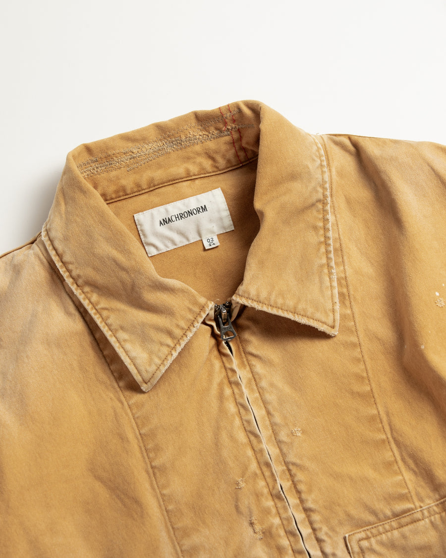 【 商品名：リメイクデトロイトダックジャケット 】

本製品は、ゆとりのある身幅とややクロップド丈に設計されたイエローカラーのジャケットで、インナーアイテムとのレイヤードを楽しめるバランスの良いシルエットが特徴です。生地には頒布の中でも最も薄手の11号帆布生地を使用しており、強度・耐久性に優れるとともに、着用を重ねるごとにアタリなどの経年変化を味わえる素材です。さらに、水や薬品の使用量を抑えながら生地の凹凸部分のアタリを強調し、同時に自然な脱色感を生み出す特殊エイジング加工を施し、加えてサンフェードによるダメージ加工も行うことで、より深みのある表情に仕上げています。