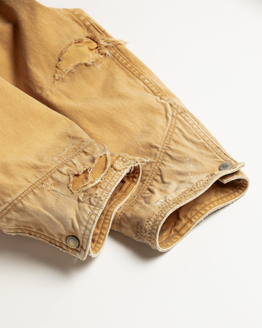 【 商品名：リメイクデトロイトダックジャケット 】

本製品は、ゆとりのある身幅とややクロップド丈に設計されたイエローカラーのジャケットで、インナーアイテムとのレイヤードを楽しめるバランスの良いシルエットが特徴です。生地には頒布の中でも最も薄手の11号帆布生地を使用しており、強度・耐久性に優れるとともに、着用を重ねるごとにアタリなどの経年変化を味わえる素材です。さらに、水や薬品の使用量を抑えながら生地の凹凸部分のアタリを強調し、同時に自然な脱色感を生み出す特殊エイジング加工を施し、加えてサンフェードによるダメージ加工も行うことで、より深みのある表情に仕上げています。