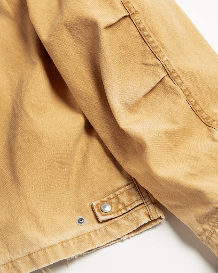 【 商品名：リメイクデトロイトダックジャケット 】

本製品は、ゆとりのある身幅とややクロップド丈に設計されたイエローカラーのジャケットで、インナーアイテムとのレイヤードを楽しめるバランスの良いシルエットが特徴です。生地には頒布の中でも最も薄手の11号帆布生地を使用しており、強度・耐久性に優れるとともに、着用を重ねるごとにアタリなどの経年変化を味わえる素材です。さらに、水や薬品の使用量を抑えながら生地の凹凸部分のアタリを強調し、同時に自然な脱色感を生み出す特殊エイジング加工を施し、加えてサンフェードによるダメージ加工も行うことで、より深みのある表情に仕上げています。