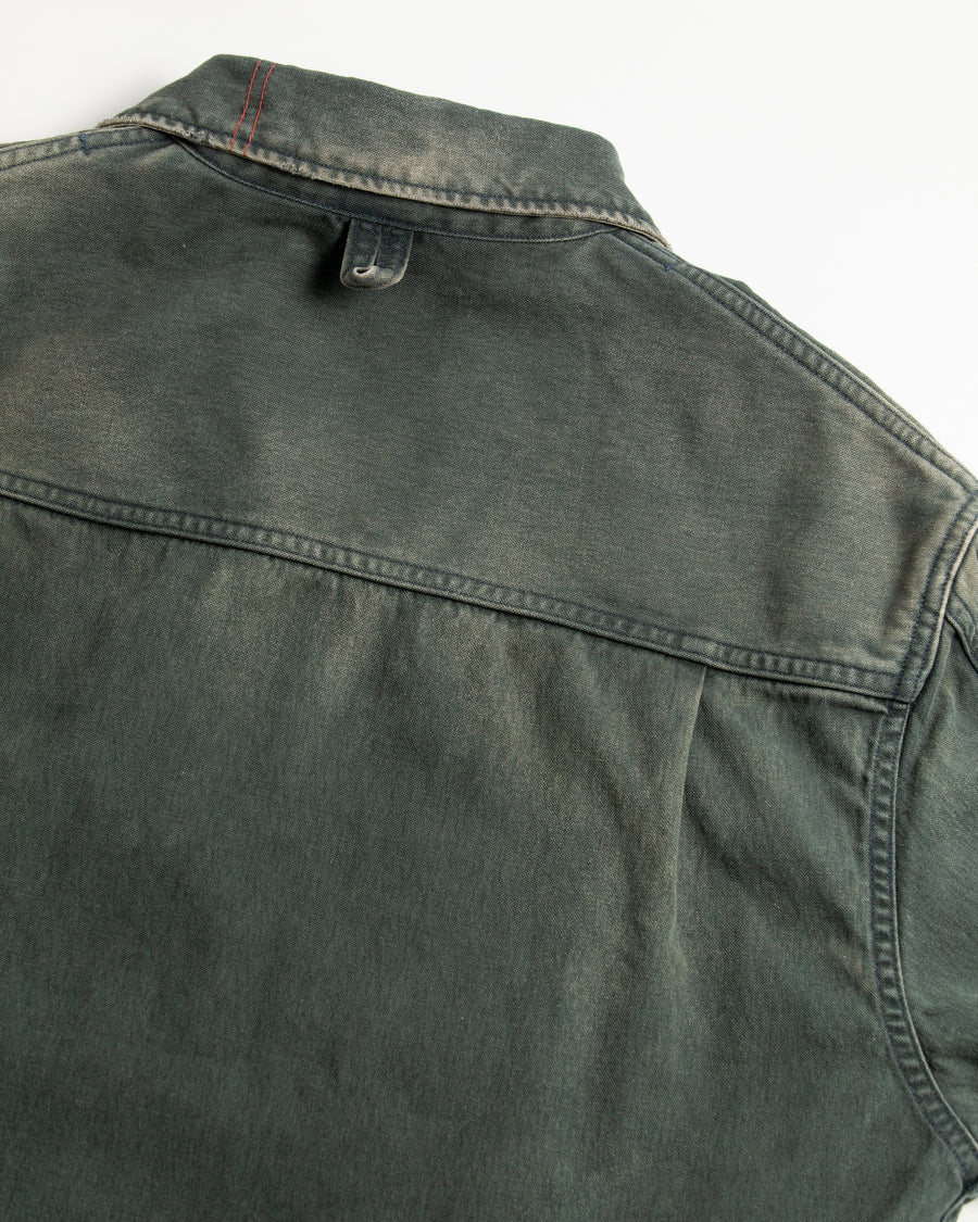 【 商品名：リメイクデトロイトダックジャケット 】

本製品は、ゆとりのある身幅とややクロップド丈に設計されたブラックカラーのジャケットで、インナーアイテムとのレイヤードを楽しめるバランスの良いシルエットが特徴です。生地には頒布の中でも最も薄手の11号帆布生地を採用しており、強度・耐久性に優れ、着用を重ねるごとにアタリなどの経年変化を味わえる素材です。さらに、水や薬品の使用量を抑えながら生地の凹凸部分のアタリを強調し、同時に自然な脱色感を生み出す特殊エイジング加工を施し、加えてサンフェードによるダメージ加工を加えることで、より奥行きのある表情に仕上げています。