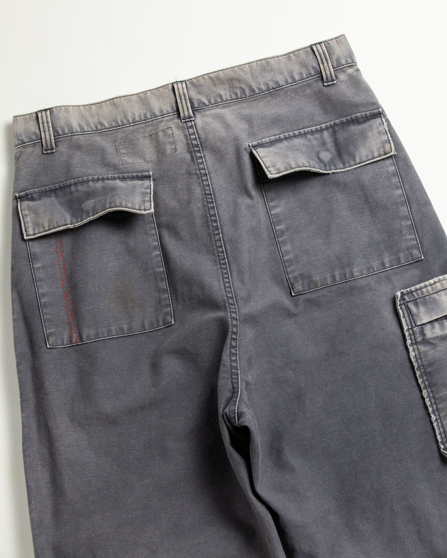 フラップポケットや膝のタック、裾のドローコードなど、ミリタリーのディテールをふんだんに取り入れた一本。内側に配置されることの多いポケットをあえて外側に設けたカーゴポケットが特徴です。ムラ糸で織り上げたバックサテン生地は、ハリとコシのある質感が魅力。さらに、水や薬品の使用を抑えながら生地の凹凸を際立たせる特殊エイジング加工を施し、深みのあるネイビーカラーに仕上げています。