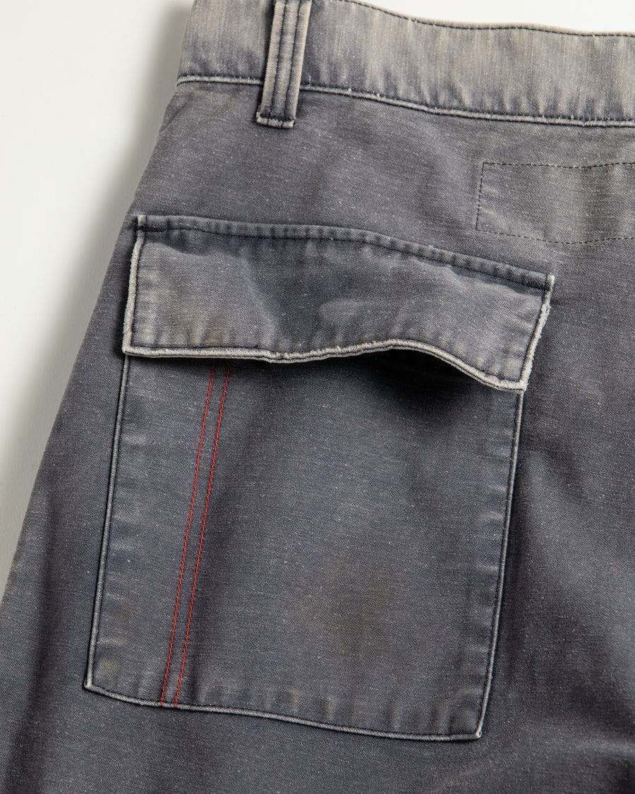 フラップポケットや膝のタック、裾のドローコードなど、ミリタリーのディテールをふんだんに取り入れた一本。内側に配置されることの多いポケットをあえて外側に設けたカーゴポケットが特徴です。ムラ糸で織り上げたバックサテン生地は、ハリとコシのある質感が魅力。さらに、水や薬品の使用を抑えながら生地の凹凸を際立たせる特殊エイジング加工を施し、深みのあるネイビーカラーに仕上げています。