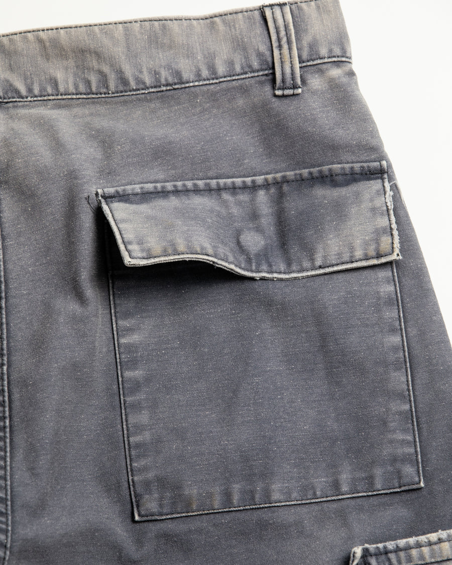 フラップポケットや膝のタック、裾のドローコードなど、ミリタリーのディテールをふんだんに取り入れた一本。内側に配置されることの多いポケットをあえて外側に設けたカーゴポケットが特徴です。ムラ糸で織り上げたバックサテン生地は、ハリとコシのある質感が魅力。さらに、水や薬品の使用を抑えながら生地の凹凸を際立たせる特殊エイジング加工を施し、深みのあるネイビーカラーに仕上げています。