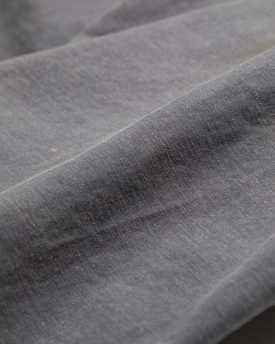 フラップポケットや膝のタック、裾のドローコードなど、ミリタリーのディテールをふんだんに取り入れた一本。内側に配置されることの多いポケットをあえて外側に設けたカーゴポケットが特徴です。ムラ糸で織り上げたバックサテン生地は、ハリとコシのある質感が魅力。さらに、水や薬品の使用を抑えながら生地の凹凸を際立たせる特殊エイジング加工を施し、深みのあるネイビーカラーに仕上げています。