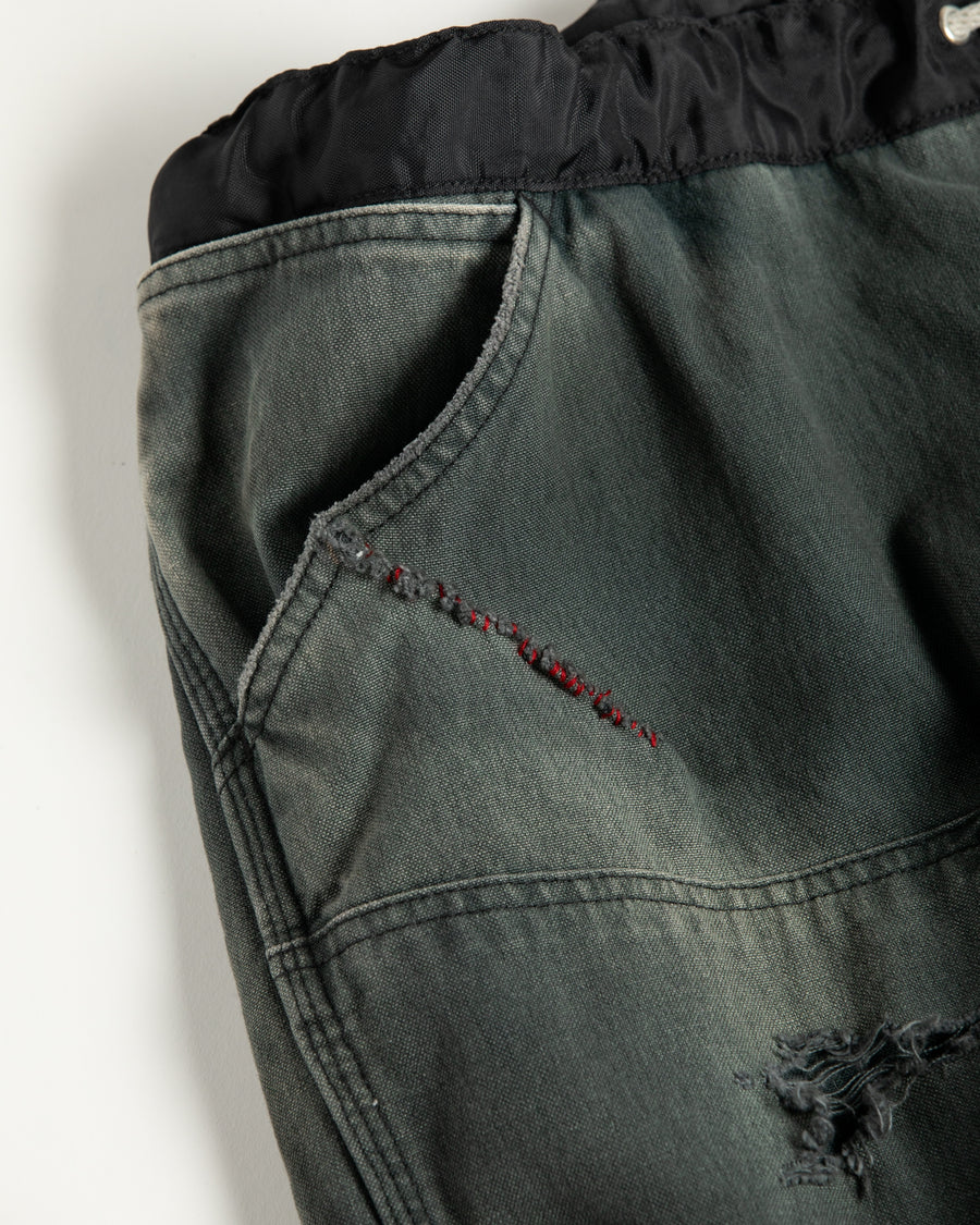 【 商品名：リメイクダブルニーダックペインターパンツ 】

本製品は、レングスをやや長めに設定したブラックカラーのペインターパンツです。ウエスト部分にはナイロンオックス生地で切り替えを施し、ワーク感を抑えつつバランスの良いデザインに仕上げています。生地には頒布の中でも最も薄手の11号帆布生地を使用しており、強度・耐久性に優れるだけでなく、着用を重ねるごとにアタリなどの経年変化を楽しめる素材です。また、水や薬品の使用量を抑えながら生地の凹凸部分のアタリを強調し、同時に自然な脱色感を与える特殊エイジング加工に加え、サンフェードによるダメージ加工も施すことで、より味わい深い表情に仕上げています。