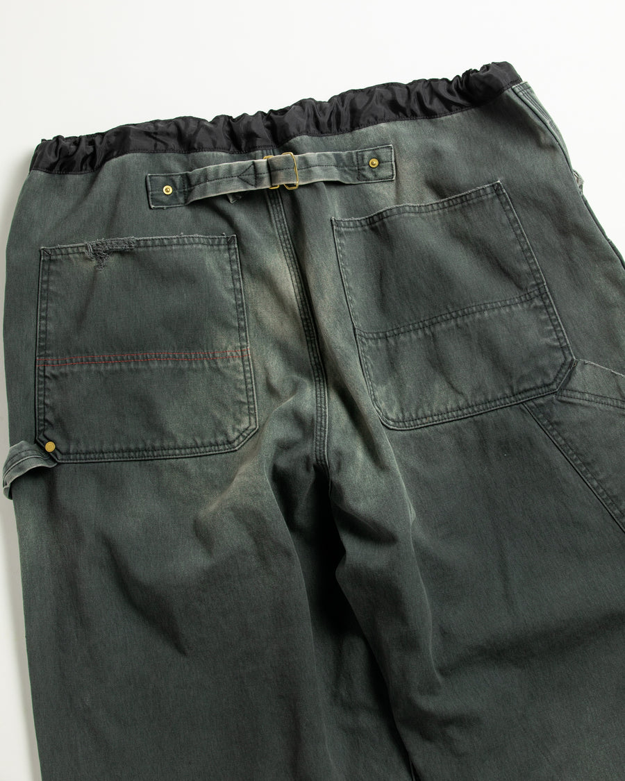 【 商品名：リメイクダブルニーダックペインターパンツ 】

本製品は、レングスをやや長めに設定したブラックカラーのペインターパンツです。ウエスト部分にはナイロンオックス生地で切り替えを施し、ワーク感を抑えつつバランスの良いデザインに仕上げています。生地には頒布の中でも最も薄手の11号帆布生地を使用しており、強度・耐久性に優れるだけでなく、着用を重ねるごとにアタリなどの経年変化を楽しめる素材です。また、水や薬品の使用量を抑えながら生地の凹凸部分のアタリを強調し、同時に自然な脱色感を与える特殊エイジング加工に加え、サンフェードによるダメージ加工も施すことで、より味わい深い表情に仕上げています。