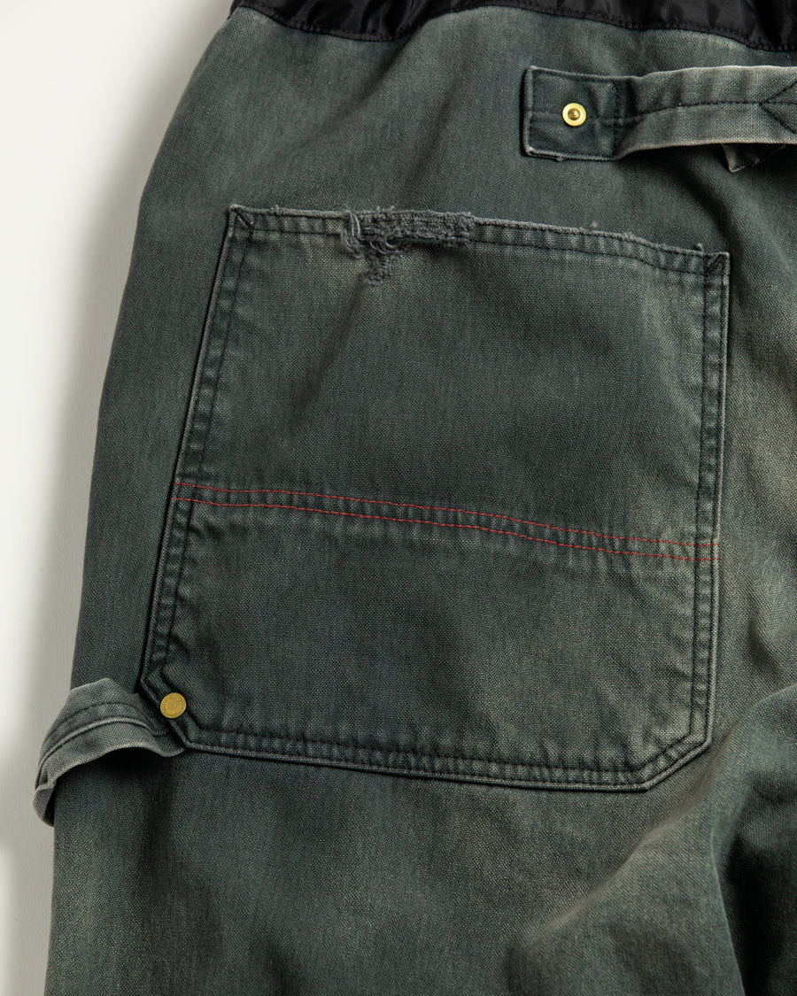 【 商品名：リメイクダブルニーダックペインターパンツ 】

本製品は、レングスをやや長めに設定したブラックカラーのペインターパンツです。ウエスト部分にはナイロンオックス生地で切り替えを施し、ワーク感を抑えつつバランスの良いデザインに仕上げています。生地には頒布の中でも最も薄手の11号帆布生地を使用しており、強度・耐久性に優れるだけでなく、着用を重ねるごとにアタリなどの経年変化を楽しめる素材です。また、水や薬品の使用量を抑えながら生地の凹凸部分のアタリを強調し、同時に自然な脱色感を与える特殊エイジング加工に加え、サンフェードによるダメージ加工も施すことで、より味わい深い表情に仕上げています。