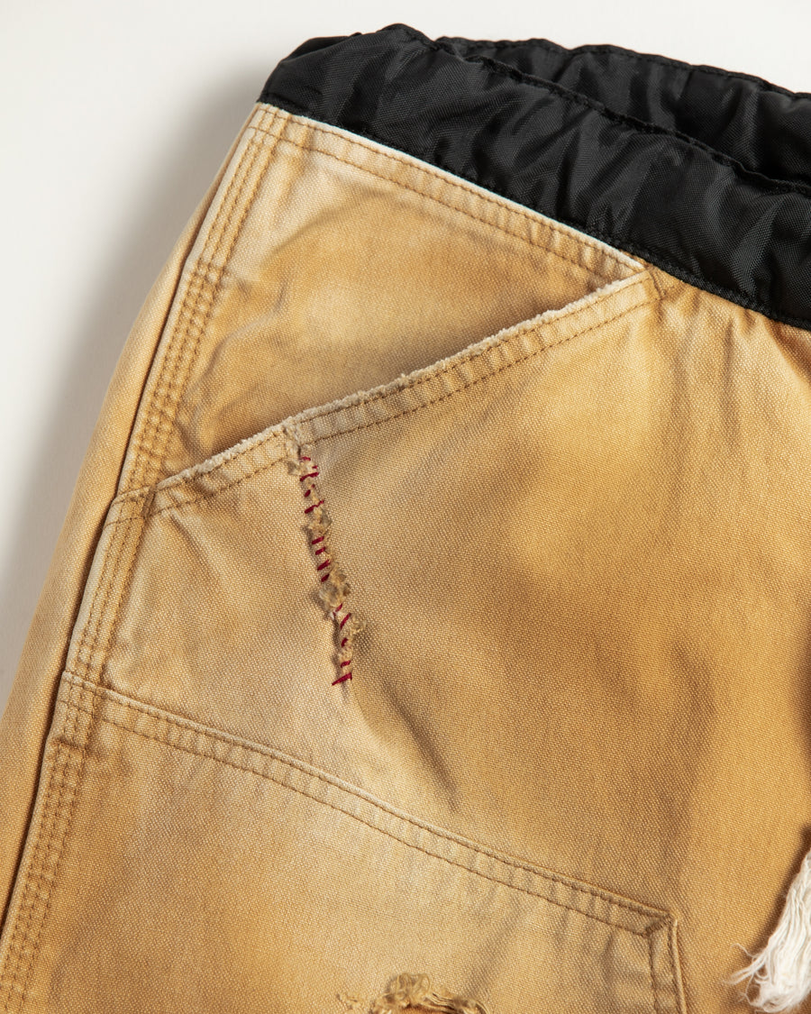 【 商品名：リメイクダブルニーダックペインターパンツ 】

本製品は、レングスをやや長めに設定したイエローカラーのペインターパンツです。ウエスト部分にはナイロンオックス生地で切り替えを施し、ワーク感を抑えたバランスの良いデザインに仕上げています。生地には頒布の中でも最も薄手の11号帆布生地を使用しており、強度・耐久性に優れるだけでなく、着用を重ねるごとにアタリなどの経年変化を味わえる素材です。また、水や薬品の使用量を抑えながら生地の凹凸部分のアタリを強調し、同時に自然な脱色感を与える特殊エイジング加工に加え、サンフェードによるダメージ加工も施すことで、より深みのある表情に仕上げています。