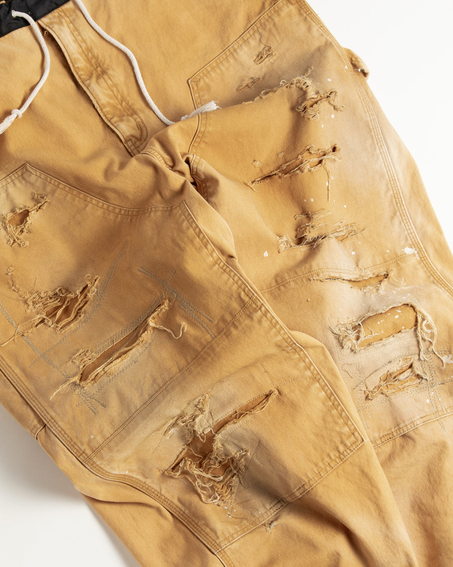 【 商品名：リメイクダブルニーダックペインターパンツ 】

本製品は、レングスをやや長めに設定したイエローカラーのペインターパンツです。ウエスト部分にはナイロンオックス生地で切り替えを施し、ワーク感を抑えたバランスの良いデザインに仕上げています。生地には頒布の中でも最も薄手の11号帆布生地を使用しており、強度・耐久性に優れるだけでなく、着用を重ねるごとにアタリなどの経年変化を味わえる素材です。また、水や薬品の使用量を抑えながら生地の凹凸部分のアタリを強調し、同時に自然な脱色感を与える特殊エイジング加工に加え、サンフェードによるダメージ加工も施すことで、より深みのある表情に仕上げています。