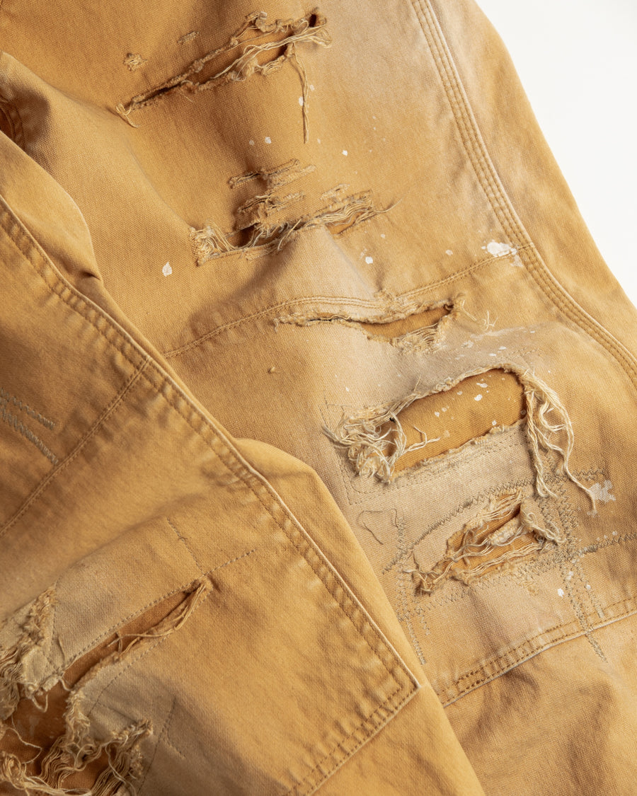 【 商品名：リメイクダブルニーダックペインターパンツ 】

本製品は、レングスをやや長めに設定したイエローカラーのペインターパンツです。ウエスト部分にはナイロンオックス生地で切り替えを施し、ワーク感を抑えたバランスの良いデザインに仕上げています。生地には頒布の中でも最も薄手の11号帆布生地を使用しており、強度・耐久性に優れるだけでなく、着用を重ねるごとにアタリなどの経年変化を味わえる素材です。また、水や薬品の使用量を抑えながら生地の凹凸部分のアタリを強調し、同時に自然な脱色感を与える特殊エイジング加工に加え、サンフェードによるダメージ加工も施すことで、より深みのある表情に仕上げています。