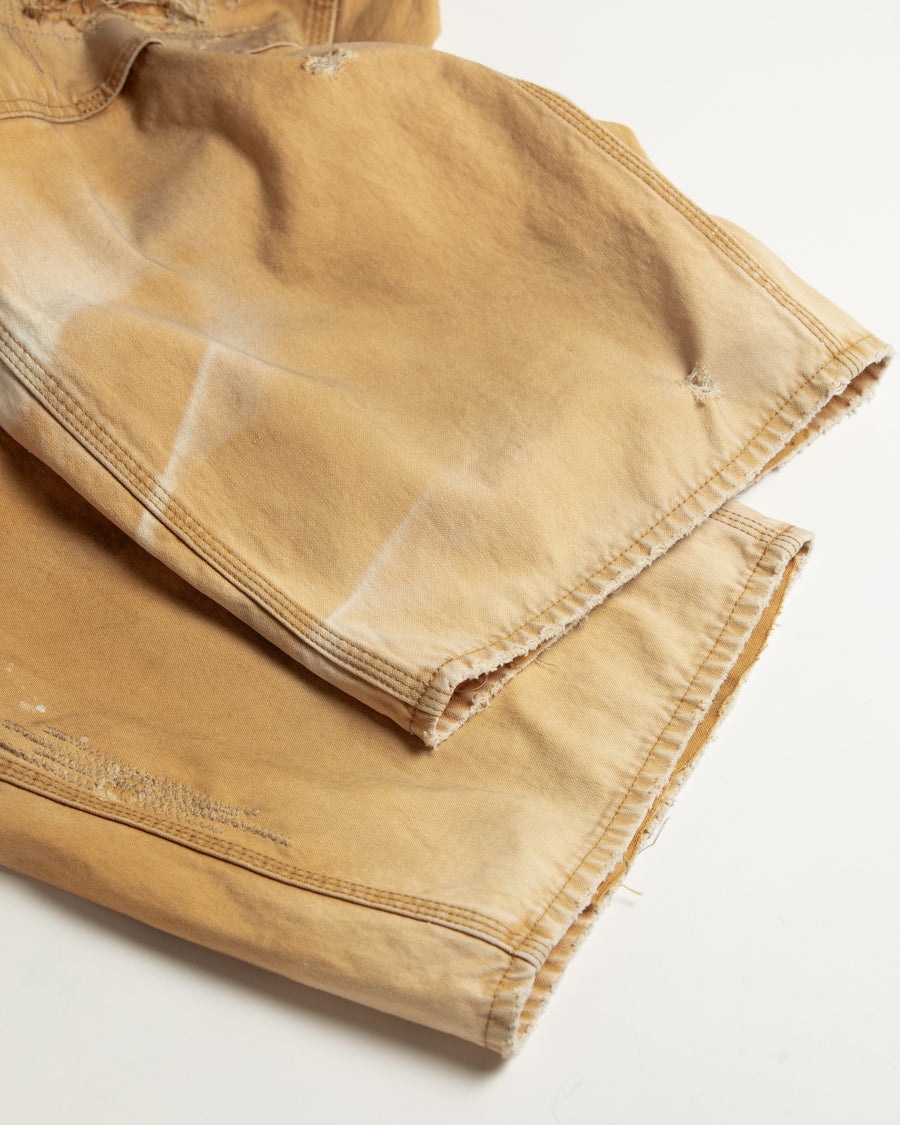 【 商品名：リメイクダブルニーダックペインターパンツ 】

本製品は、レングスをやや長めに設定したイエローカラーのペインターパンツです。ウエスト部分にはナイロンオックス生地で切り替えを施し、ワーク感を抑えたバランスの良いデザインに仕上げています。生地には頒布の中でも最も薄手の11号帆布生地を使用しており、強度・耐久性に優れるだけでなく、着用を重ねるごとにアタリなどの経年変化を味わえる素材です。また、水や薬品の使用量を抑えながら生地の凹凸部分のアタリを強調し、同時に自然な脱色感を与える特殊エイジング加工に加え、サンフェードによるダメージ加工も施すことで、より深みのある表情に仕上げています。