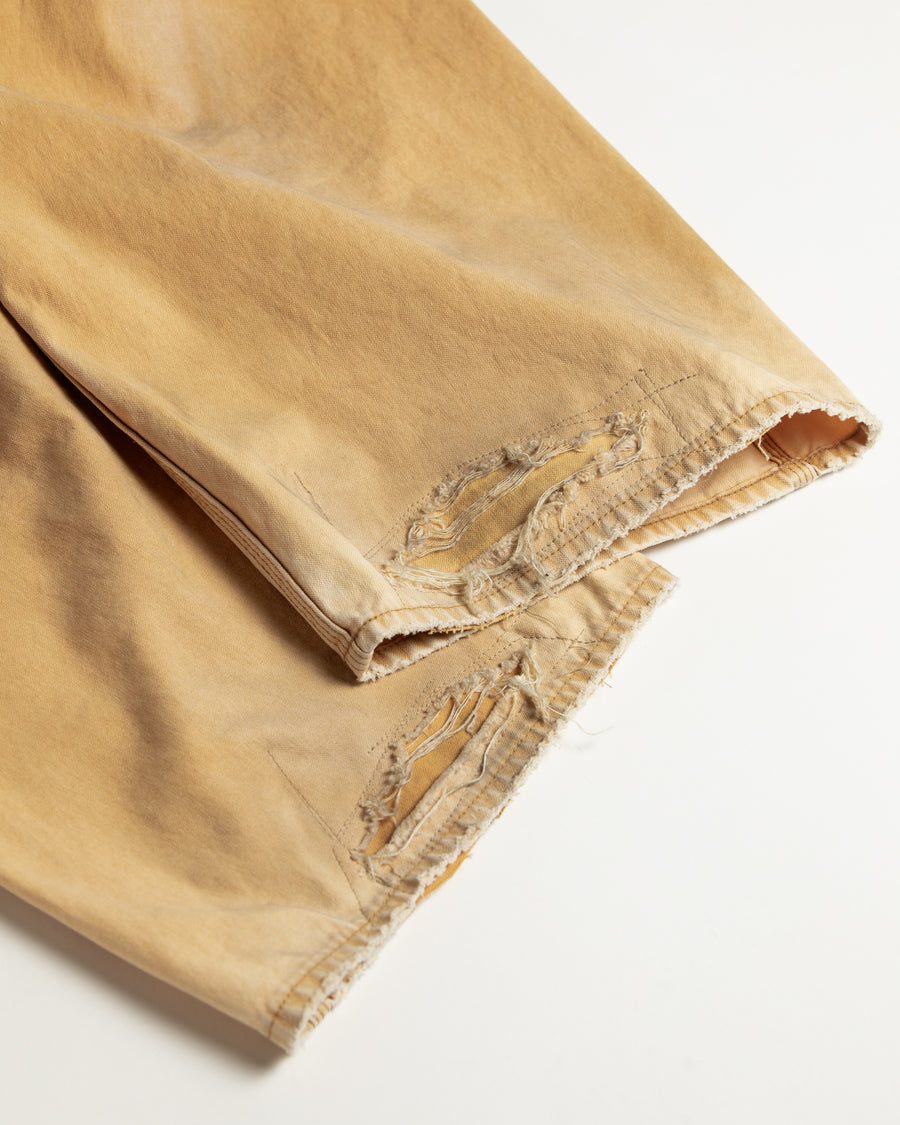 【 商品名：リメイクダブルニーダックペインターパンツ 】

本製品は、レングスをやや長めに設定したイエローカラーのペインターパンツです。ウエスト部分にはナイロンオックス生地で切り替えを施し、ワーク感を抑えたバランスの良いデザインに仕上げています。生地には頒布の中でも最も薄手の11号帆布生地を使用しており、強度・耐久性に優れるだけでなく、着用を重ねるごとにアタリなどの経年変化を味わえる素材です。また、水や薬品の使用量を抑えながら生地の凹凸部分のアタリを強調し、同時に自然な脱色感を与える特殊エイジング加工に加え、サンフェードによるダメージ加工も施すことで、より深みのある表情に仕上げています。