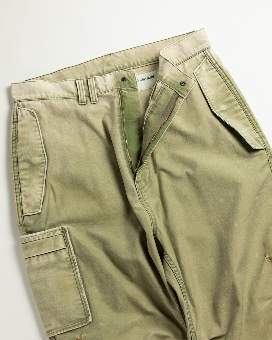 フラップポケットや膝のタック、裾のドローコードなど、ミリタリーのディテールをふんだんに取り入れた一本。内側に配置されることの多いポケットをあえて外側に設けたカーゴポケットが特徴です。ムラ糸で織り上げたバックサテン生地は、ハリとコシのある質感が魅力。さらに、水や薬品の使用を抑えながら生地の凹凸を際立たせる特殊エイジング加工を施し、深みのあるオリーブカラーに仕上げています。