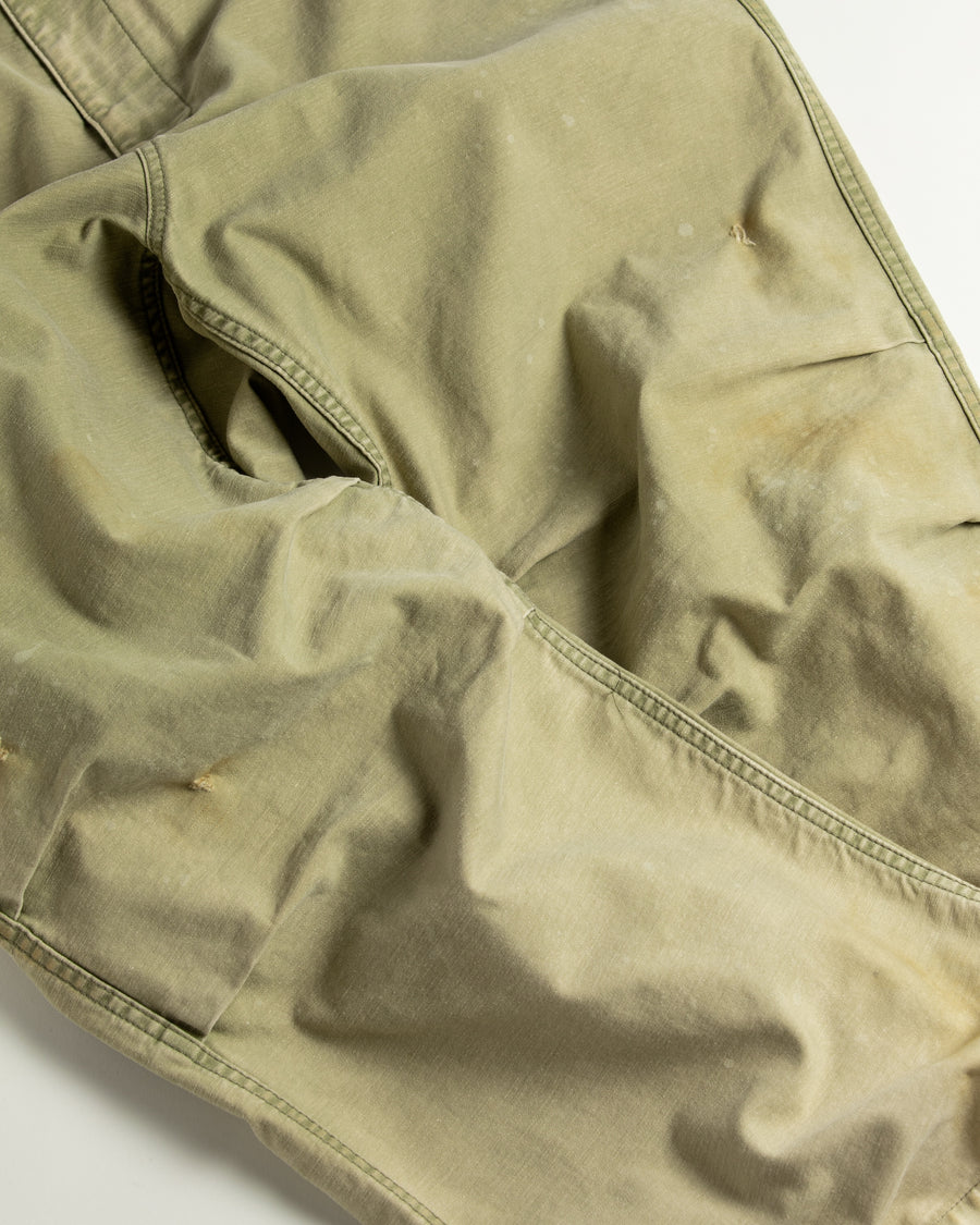フラップポケットや膝のタック、裾のドローコードなど、ミリタリーのディテールをふんだんに取り入れた一本。内側に配置されることの多いポケットをあえて外側に設けたカーゴポケットが特徴です。ムラ糸で織り上げたバックサテン生地は、ハリとコシのある質感が魅力。さらに、水や薬品の使用を抑えながら生地の凹凸を際立たせる特殊エイジング加工を施し、深みのあるオリーブカラーに仕上げています。
