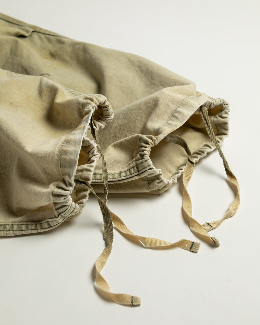 フラップポケットや膝のタック、裾のドローコードなど、ミリタリーのディテールをふんだんに取り入れた一本。内側に配置されることの多いポケットをあえて外側に設けたカーゴポケットが特徴です。ムラ糸で織り上げたバックサテン生地は、ハリとコシのある質感が魅力。さらに、水や薬品の使用を抑えながら生地の凹凸を際立たせる特殊エイジング加工を施し、深みのあるオリーブカラーに仕上げています。