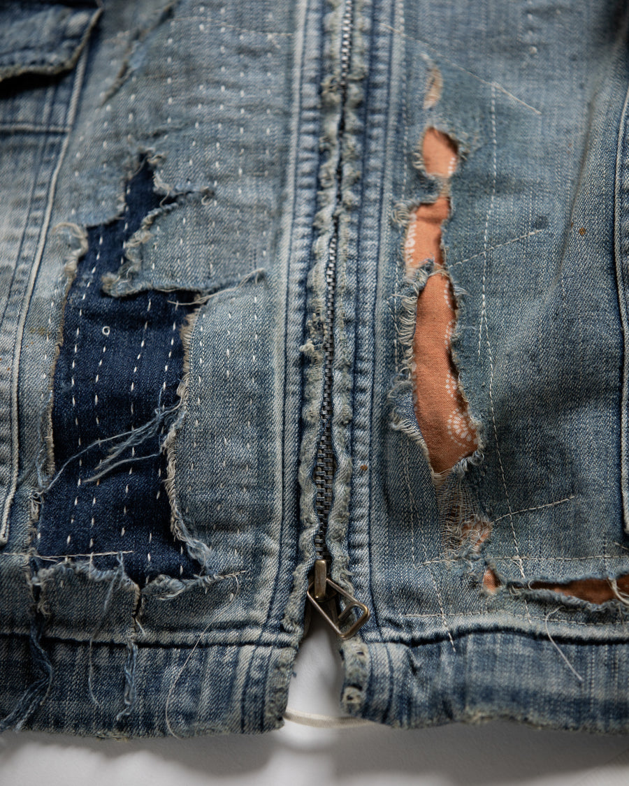 ライトオンスデニムを二重縫製で仕立てたフルジップパーカー。
経糸にジンバブエコットン100％、緯糸に綿麻混紡糸を用いたデニムは、シャープなムラ感と粗野な風合いでヴィンテージ感を演出。
全体にエイジングを施し、ハードダメージと手作業のステッチワークで仕上げたリメイク加工が特徴です。