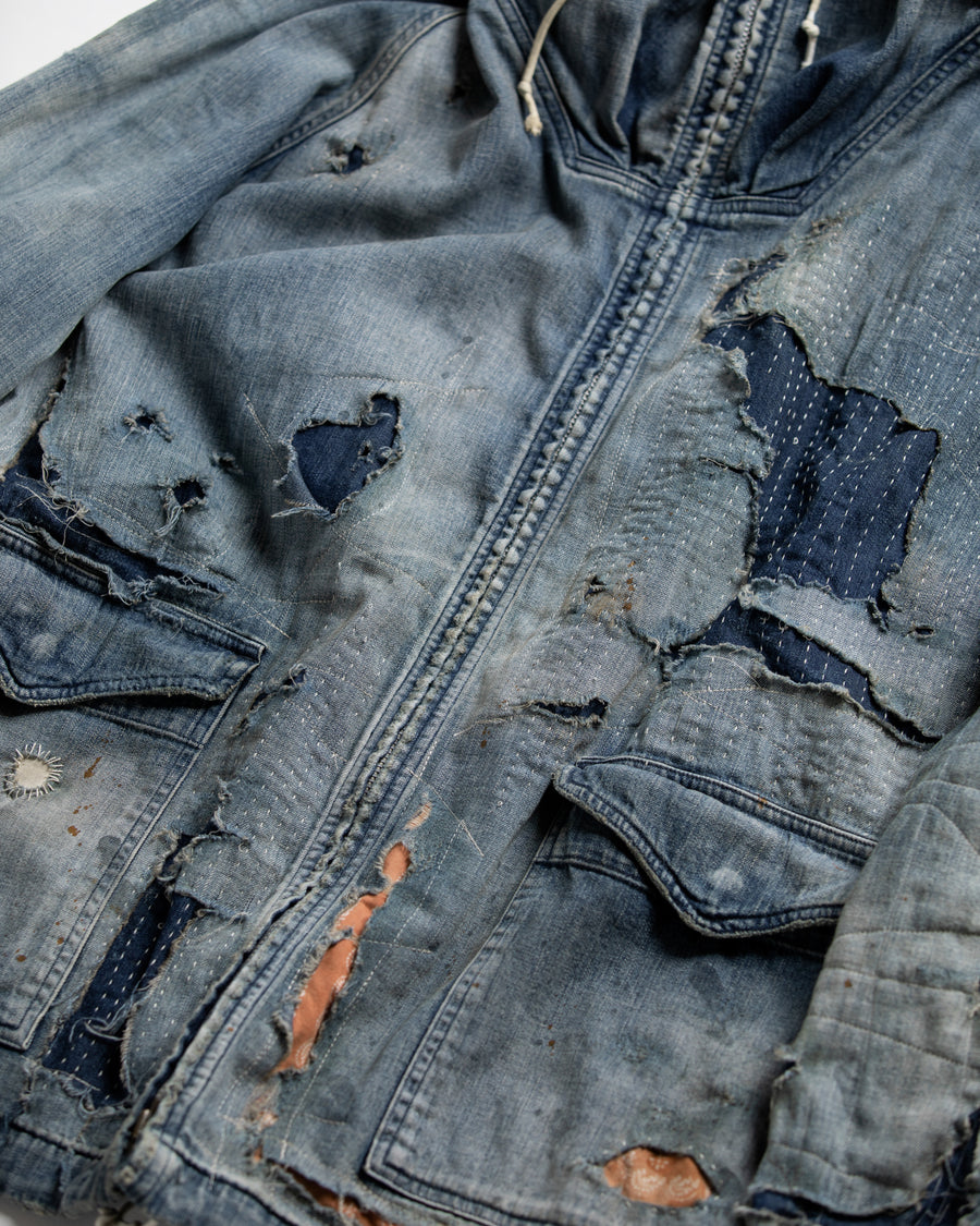 ライトオンスデニムを二重縫製で仕立てたフルジップパーカー。
経糸にジンバブエコットン100％、緯糸に綿麻混紡糸を用いたデニムは、シャープなムラ感と粗野な風合いでヴィンテージ感を演出。
全体にエイジングを施し、ハードダメージと手作業のステッチワークで仕上げたリメイク加工が特徴です。