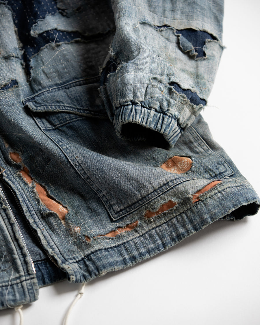 ライトオンスデニムを二重縫製で仕立てたフルジップパーカー。
経糸にジンバブエコットン100％、緯糸に綿麻混紡糸を用いたデニムは、シャープなムラ感と粗野な風合いでヴィンテージ感を演出。
全体にエイジングを施し、ハードダメージと手作業のステッチワークで仕上げたリメイク加工が特徴です。