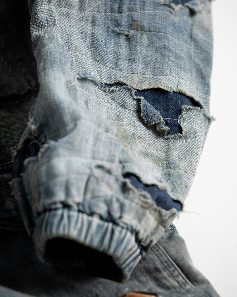 ライトオンスデニムを二重縫製で仕立てたフルジップパーカー。
経糸にジンバブエコットン100％、緯糸に綿麻混紡糸を用いたデニムは、シャープなムラ感と粗野な風合いでヴィンテージ感を演出。
全体にエイジングを施し、ハードダメージと手作業のステッチワークで仕上げたリメイク加工が特徴です。