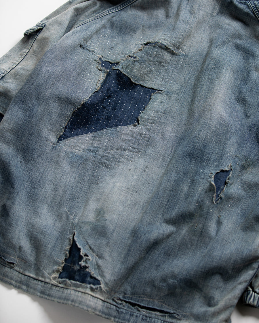 ライトオンスデニムを二重縫製で仕立てたフルジップパーカー。
経糸にジンバブエコットン100％、緯糸に綿麻混紡糸を用いたデニムは、シャープなムラ感と粗野な風合いでヴィンテージ感を演出。
全体にエイジングを施し、ハードダメージと手作業のステッチワークで仕上げたリメイク加工が特徴です。