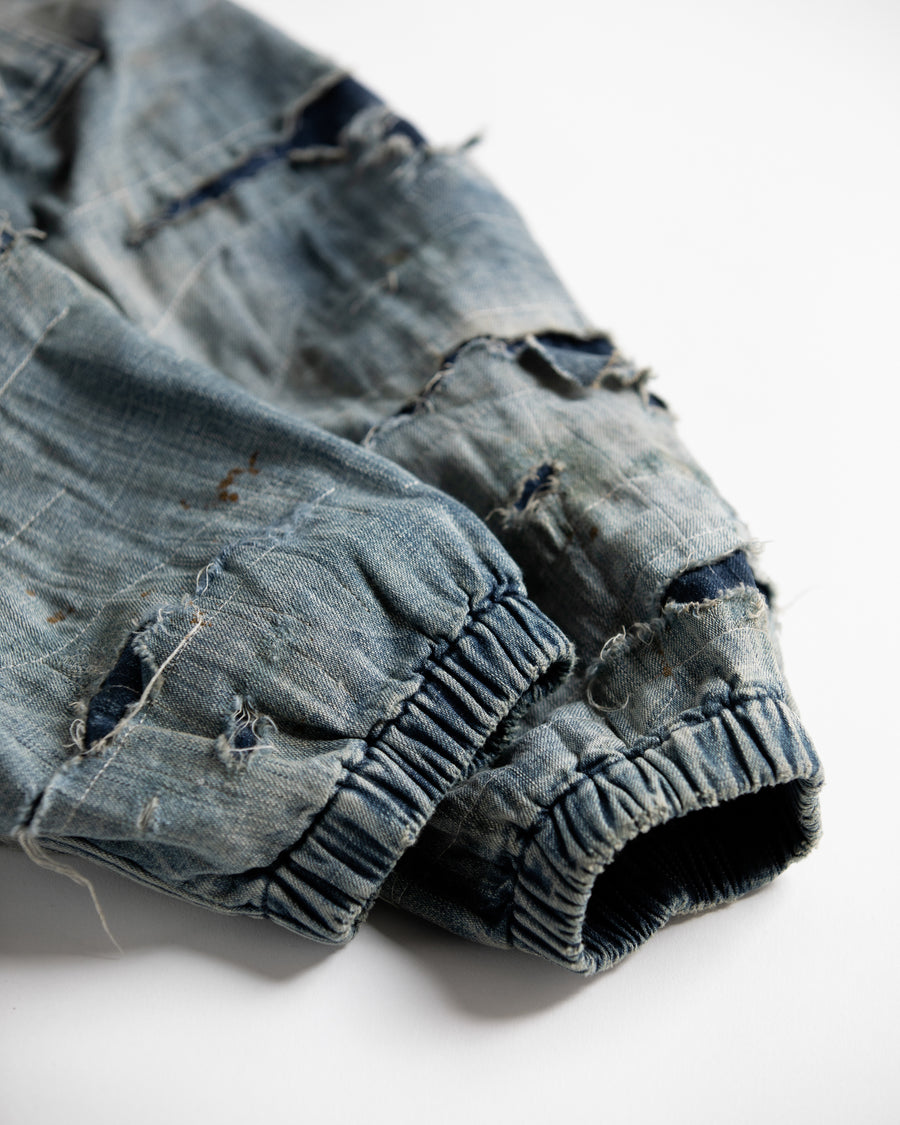 ライトオンスデニムを二重縫製で仕立てたフルジップパーカー。
経糸にジンバブエコットン100％、緯糸に綿麻混紡糸を用いたデニムは、シャープなムラ感と粗野な風合いでヴィンテージ感を演出。
全体にエイジングを施し、ハードダメージと手作業のステッチワークで仕上げたリメイク加工が特徴です。