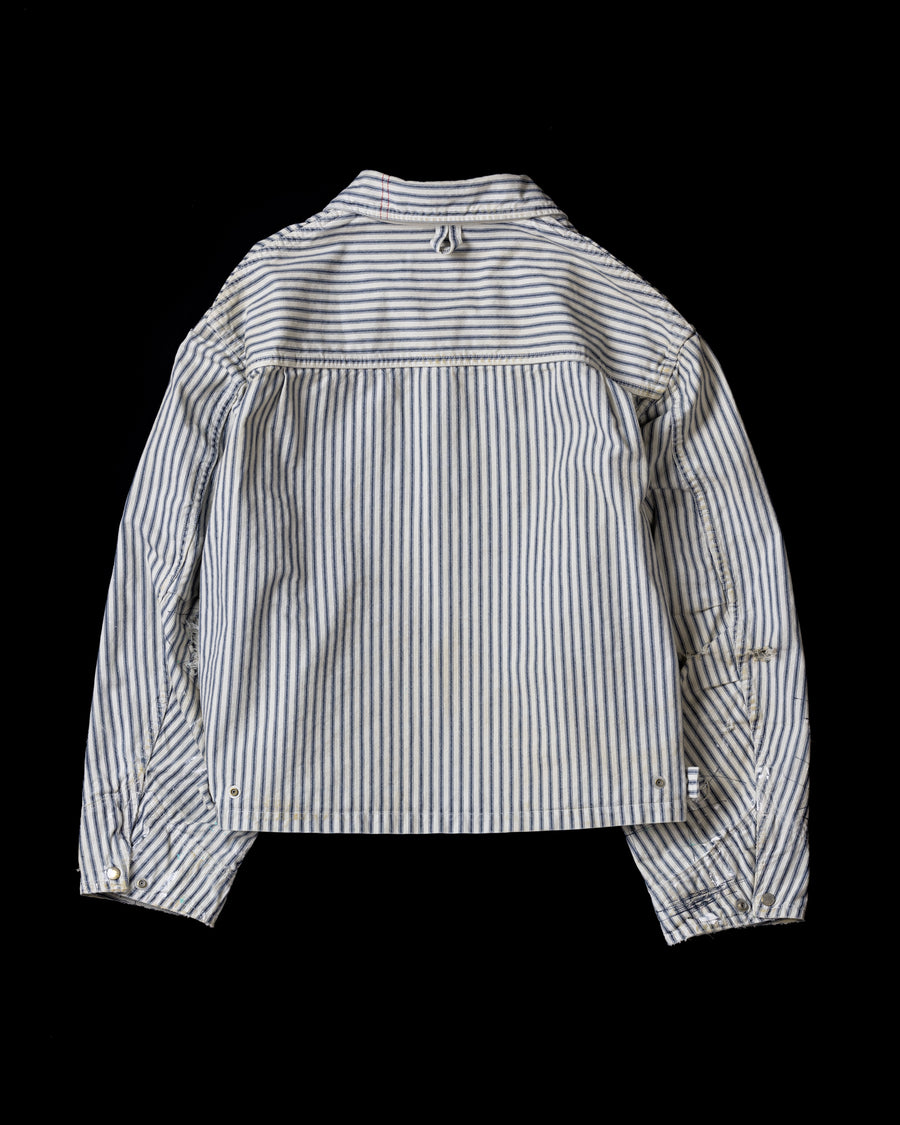 ゆとりある身幅とややクロップド丈でレイヤードを楽しめるデザインにしたヒッコリージャケット。
岡山県製9ozヒッコリーストライプ生地を使用し、ハリのあるしっかりとした風合いが特徴。
全体にエイジングとハードダメージを施し、手作業のステッチ補修とランダムなペンキでリアルな表情に仕上げています。