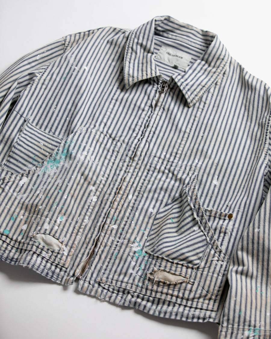 ゆとりある身幅とややクロップド丈でレイヤードを楽しめるデザインにしたヒッコリージャケット。
岡山県製9ozヒッコリーストライプ生地を使用し、ハリのあるしっかりとした風合いが特徴。
全体にエイジングとハードダメージを施し、手作業のステッチ補修とランダムなペンキでリアルな表情に仕上げています。