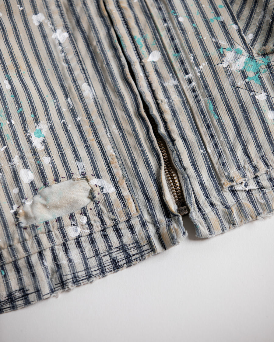 ゆとりある身幅とややクロップド丈でレイヤードを楽しめるデザインにしたヒッコリージャケット。
岡山県製9ozヒッコリーストライプ生地を使用し、ハリのあるしっかりとした風合いが特徴。
全体にエイジングとハードダメージを施し、手作業のステッチ補修とランダムなペンキでリアルな表情に仕上げています。